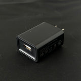 Black USB wall charger block on black background, single USB port, compact power adapter