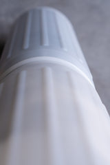 Close-up of a white water filter cartridge on a gray background, ridged texture visible