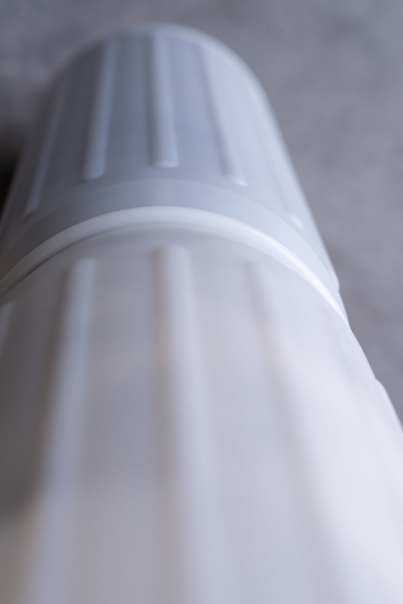 Close-up of a white water filter cartridge on a gray background, ridged texture visible