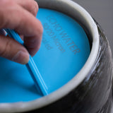 Hand holding blue hydrogen water filter cartridge with micron rating visible