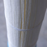 Close-up of pleated water filter cartridge with vertical white fibers and plastic band