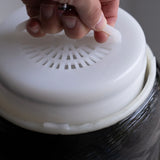 Hand lifting white filter lid on hydrogen water system close-up