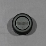 Black circular hydrogen water device lid on gray background, close-up product view