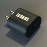 Black USB wall charger adapter with a white wavy line logo on a gray background