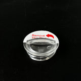 Clear plastic retention plug with 'Remove This Plug' label on black background