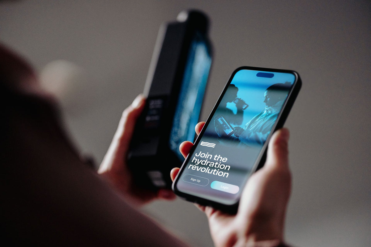 Hands holding a smartphone with hydration technology app and a hydrogen water device